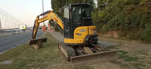 Mini excavator digging beside a road