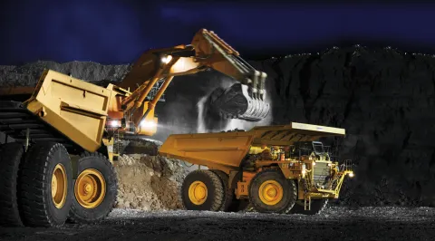 Hitachi mining excavator loading haul trucks in a coal mine