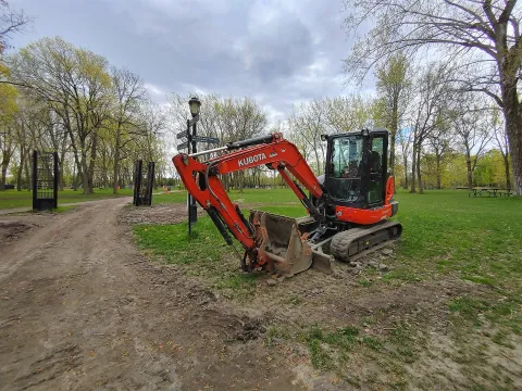 Orange Kubota compact excavator working in a city park